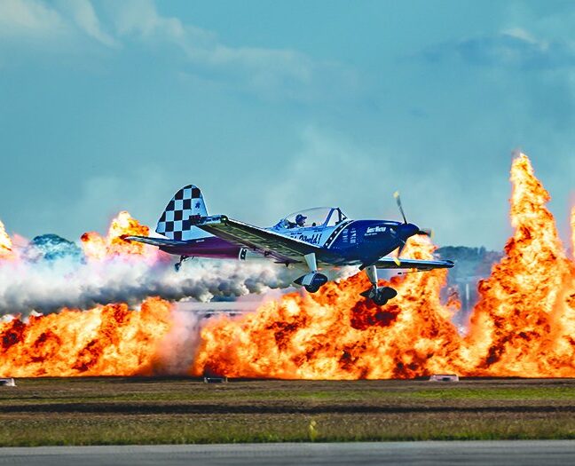 Aerobatic plane flying past a wall of fire at the Stuart Air Show