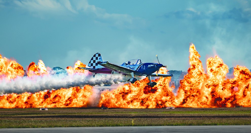 Aerobatic plane flying past a wall of fire at the Stuart Air Show