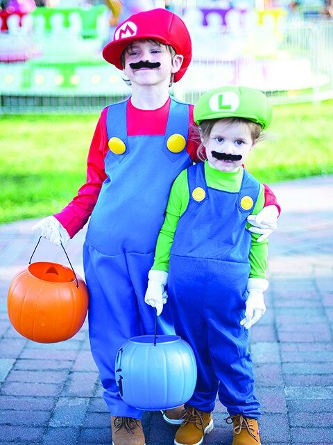 Two children in Mario and Luigi costumes trick-or-treating at Spookyville