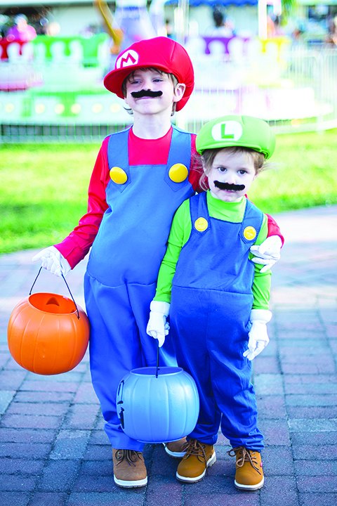 Two children in Mario and Luigi costumes trick-or-treating at Spookyville